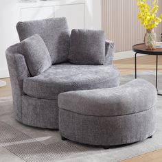 a grey chair and ottoman in a living room with yellow flowers on the side table