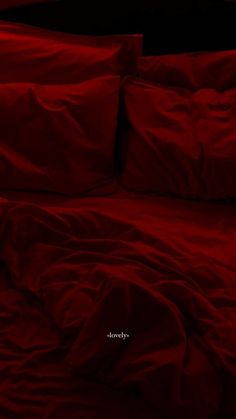 a bed with red sheets and pillows on it