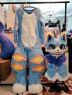 two stuffed animals sitting next to each other in front of a clothing rack with clothes on it