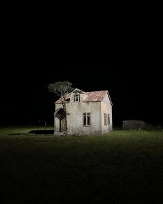 an old house sitting in the middle of a field at night