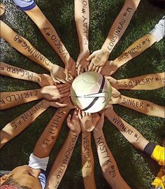 a group of people holding a soccer ball in the middle of a circle with words written on it