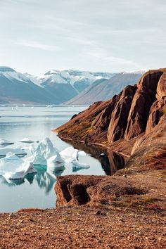 an iceberg floating in the water near mountains