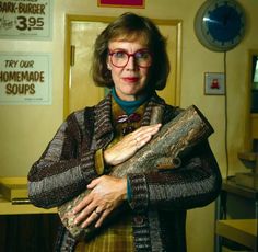 an older woman wearing glasses and holding a piece of wood