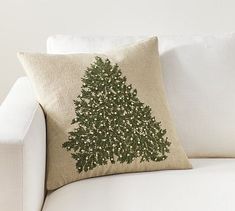 a white couch with a green christmas tree pillow on it's back and side