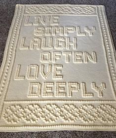 a crocheted afghan with words written in white on the front and back side