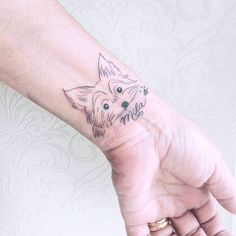 a small dog tattoo on the left wrist