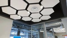 the ceiling in an office building is decorated with hexagonal lights and black accents