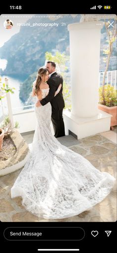 a bride and groom kissing in front of a balcony overlooking the ocean on their wedding day