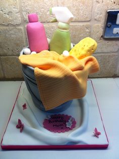 a birthday cake made to look like a bucket full of cleaning supplies and personal care items