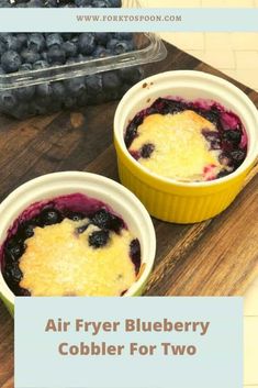 two bowls of blueberry cobbler on a cutting board with the words air fryer blueberry cobbler for two