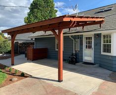 an outdoor patio with a pergolan attached to the side of it and a garage in the background