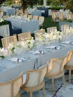 a table set up with white flowers and place settings