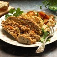 a white plate topped with meat and veggies next to a loaf of bread