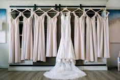 a wedding dress hanging on a rack in front of several bridesmaid gowns