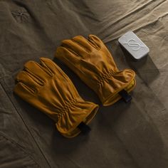 a pair of yellow gloves sitting on top of a bed next to an electronic device