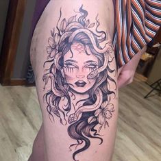 a woman's thigh with a tattoo design on her leg and the head of a snake