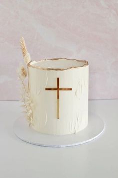 a white cake with a cross on it sitting on a plate next to a pink wall