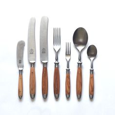 a set of knives, forks and spoons on a white surface