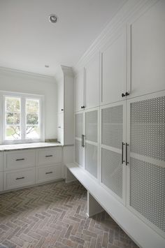 an empty kitchen with white cabinets and tile flooring on the walls, along with a large window