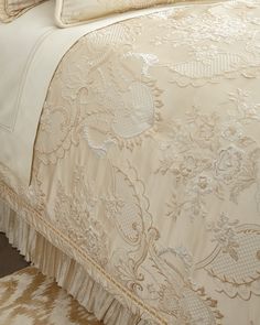 a bed with white and gold bedspread and pillows