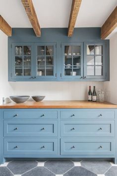 a kitchen with blue cabinets and grey tile flooring, white walls and wooden beams