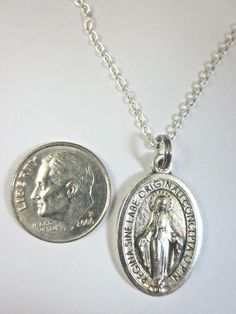 a coin is sitting next to a necklace with an image of the virgin mary on it