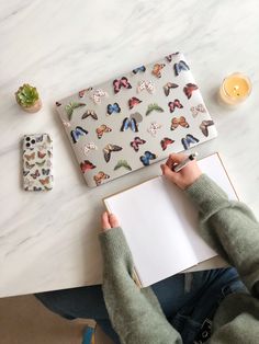 a person sitting at a table with an open laptop and notebook in front of them