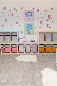 a child's playroom with toys and storage bins on the floor in front of a hot air balloon wallpaper