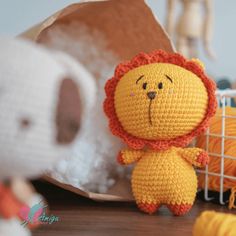 a crocheted lion sits next to some yarns and a stuffed animal on a table