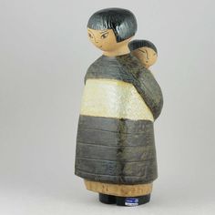 a ceramic figurine of a woman holding a child in her arms on a white background