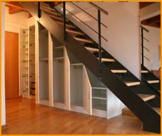 an empty room with some shelves under the stairs