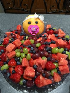 a cake made to look like a face with fruit in the shape of grapes, strawberries and watermelon