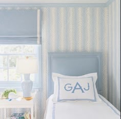 a bedroom with blue and white wallpaper has a lamp on the side table next to the bed