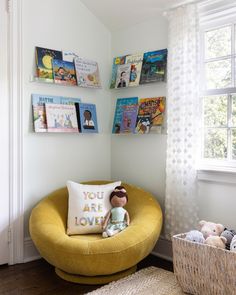 a child's room with books on the wall and a yellow chair in front