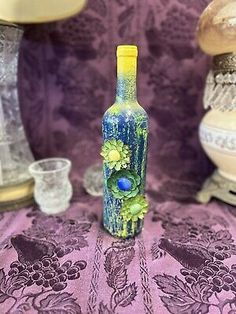 a glass bottle sitting on top of a table next to two vases and glasses