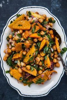 a white bowl filled with chickpeas and spinach on top of a table