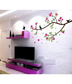 a tv sitting on top of a purple shelf next to a wall with flowers painted on it