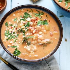 two bowls filled with soup and garnishes on top of a blue table