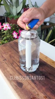 a person lighting a candle in a glass jar