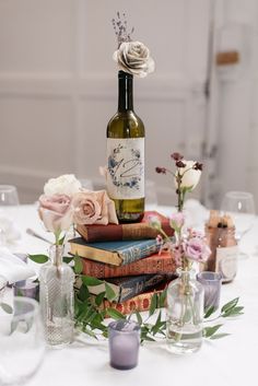 a table topped with lots of books and vases filled with flowers