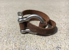 Strap on some style with our Leather Shackle Wrap Bracelet. This unique accessory adds a touch of edgy elegance to any outfit, perfect for those who are both playful and fashion-forward. Wraps around the wrist for a secure fit, making it both stylish and functional. Stainless steel shackle accentuated with brown leather. A great everyday accessory that can be dressed up or dressed down. Casual Jewelry With Adjustable Leather Strap, Adjustable Brown Metal Cuff Bracelet, Adjustable Brown Metal Wrap Bracelet, Adjustable Vintage Bracelets, Leather Strap Bracelet Jewelry For Everyday, Leather Strap Bracelet For Everyday Use, Adjustable Waxed Finish Bracelets For Everyday, Everyday Leather Strap Bracelet Jewelry, Everyday Leather Strap Bracelet