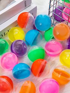 many different colored plastic balls are on the floor next to a book and some other items