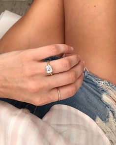 a woman's hand with a gold ring on her left side, sitting on a bed