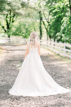 a woman in a wedding dress is walking down the road with her back to the camera