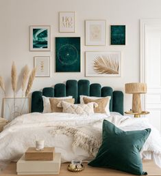 a bed with green headboard and pillows in a room filled with pictures on the wall