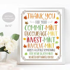 a white vase filled with flowers next to a framed sign that says thank you for your commit mintt