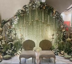 an elaborately decorated stage set with two chairs and flowers on the wall behind it