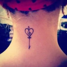 a woman's back neck with a small key and heart tattoo on her left side