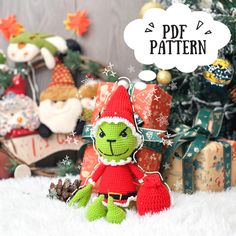 a crocheted christmas elf sitting in front of a pile of presents with a thought bubble above it