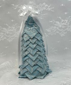 a small blue christmas tree in a clear plastic case on a white lace tablecloth